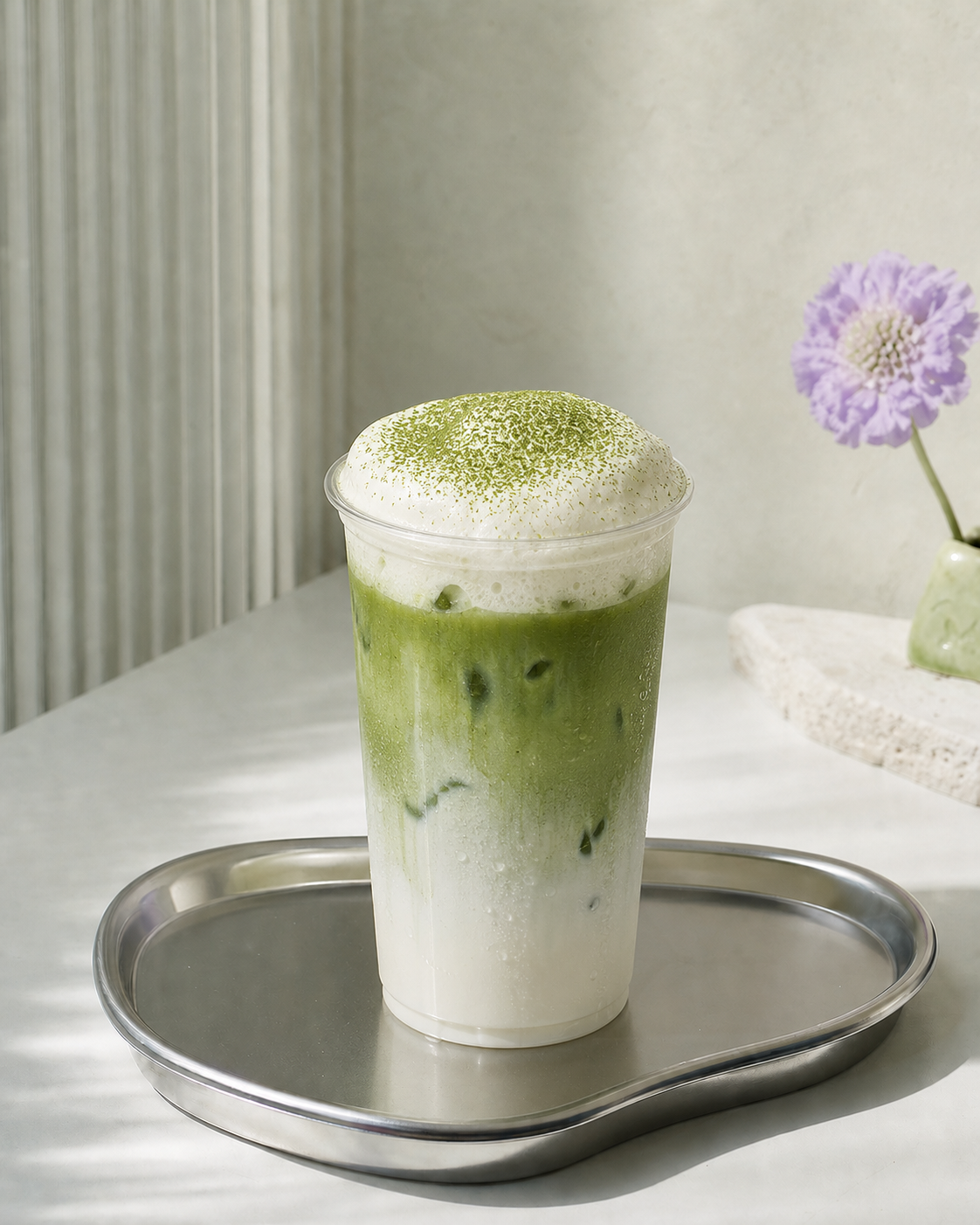 Matcha Einspänner with a thick vanilla cream cloud on a chrome tray